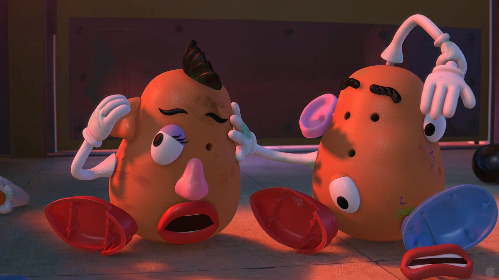 Mr. and Mrs. Potato Head on the floor with their parts in the wrong places, Mr. reaching over to fix her ear